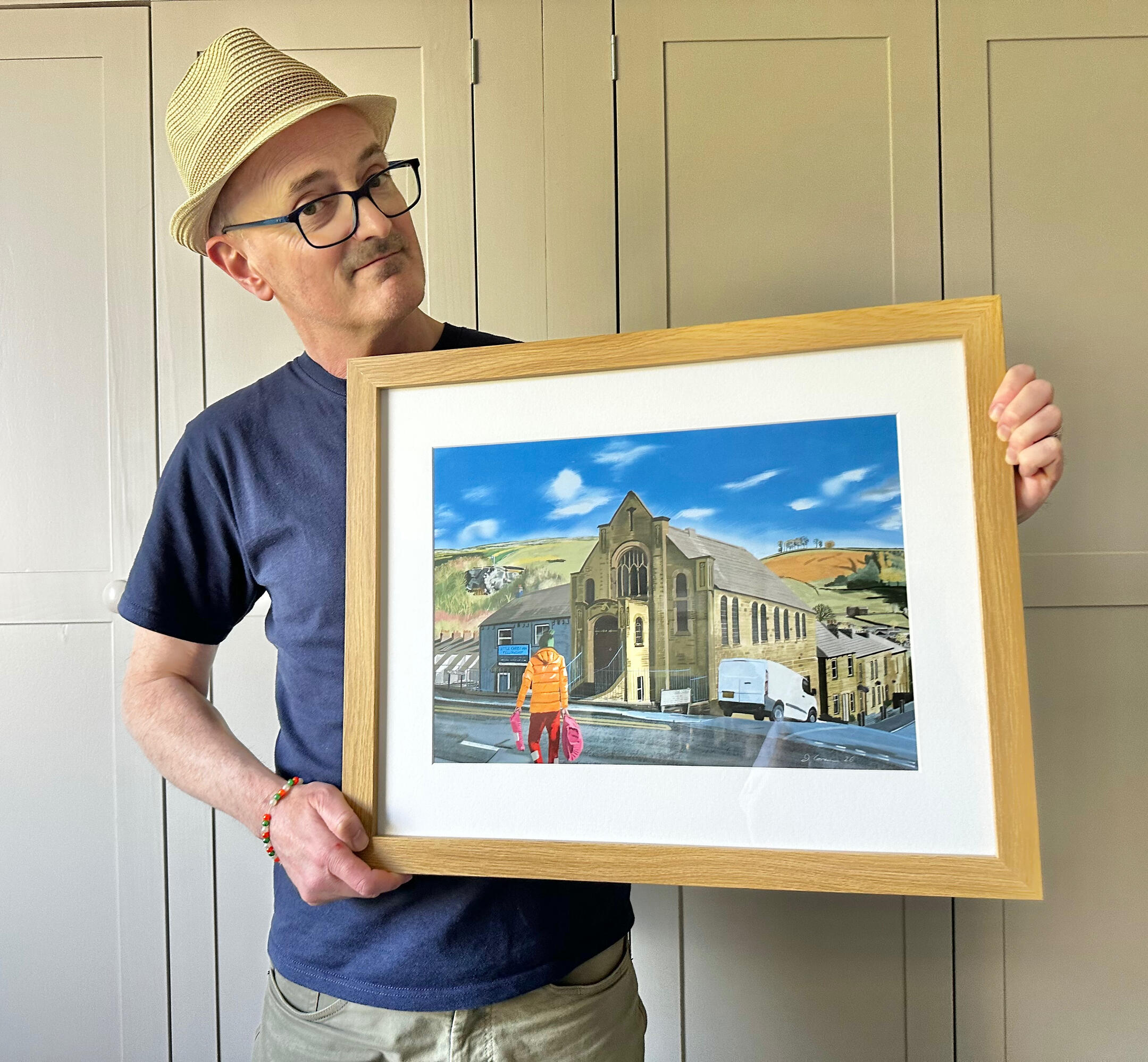 New Settle painting Artist holding framed painting of Settle North Yorkshire